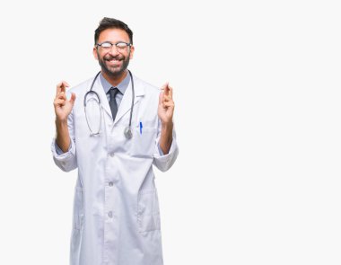 Umut ve gözleri kapalı geçiş parmaklarıyla gülümseyen izole arka plan yetişkin İspanyol doktor adam. Şans ve batıl kavramı.