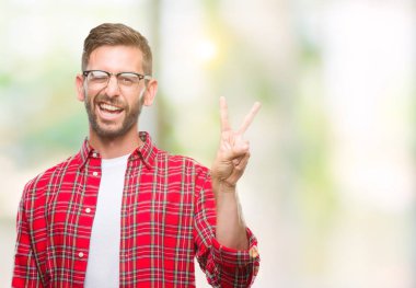 Mutlu yüz zafer işareti yaparken kameraya göz kırpıyor ile gülümseyen izole arka plan üzerinde genç yakışıklı adam. İki numaralı.