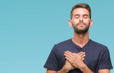 Yakışıklı delikanlı ile gülümseyen izole arka plan üzerinde kapalı gözler ve yüzünde minnettar jest ile göğüs üzerinde eller. Sağlık kavramı.