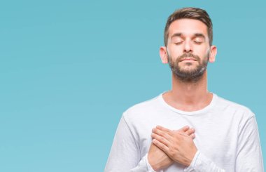 Yakışıklı delikanlı ile gülümseyen izole arka plan üzerinde kapalı gözler ve yüzünde minnettar jest ile göğüs üzerinde eller. Sağlık kavramı.