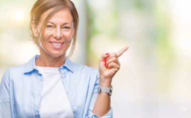 Kameraya bakarak yan el ve parmak ile işaret orta yaş İspanyol kadın kıdemli yüzünde kocaman bir gülümseme ile izole arka plan üzerinde.