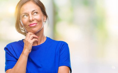 Orta yaş İspanyol kadın kıdemli çene düşünme hakkında soru, dalgın ifade üzerine el ile izole arka plan üzerinde. Düşünceli yüzüyle gülümsüyor. Şüphe kavramı.