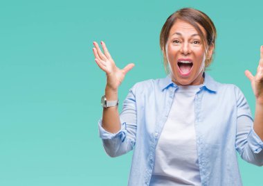 Orta yaş üst düzey İspanyol kadın deli kutluyor arka plan izole ve başarı için kaldırdı kollarını açarak hayrete ve heyecanlı çığlık gözleri açık. Kazanan kavramı