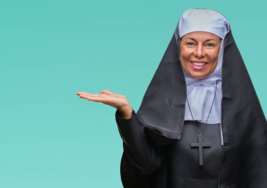 Orta yaş üst düzey Hıristiyan Katolik Rahibe kadın neşeli sunulması ve kameraya bakarak avucunun ile işaret gülümseyen izole arka plan.