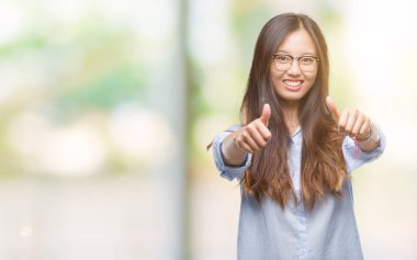 El ile pozitif jest yapıyor onaylama izole arka plan üzerinde gözlük takan genç Asya iş kadını başparmak gülümseyen ve başarı için mutlu. Kamera, kazanan jest arıyorsunuz.