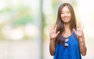 Genç Asyalı kadın gösterilen ve parmakları ile işaret izole arka plan üzerinde kendinden emin ve mutlu gülümseyerek süre on numara.