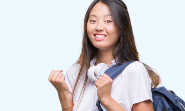 Duygu tezahürat sırt çantası ve kulaklık gurur çığlık ve zafer ve başarı çok heyecanlı, kutluyor izole arka plan üzerinde giyen genç Asyalı kadın