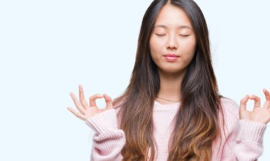 Genç Asyalı kadın izole arka plan üzerinde dinlenmek ve gülümseyen gözlerle parmak ile meditasyon jest yapıyor kapalı. Yoga kavramı.