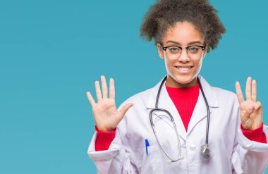 Genç afro Amerikalı doktor kadın gösterilen ve parmakları ile işaret izole arka plan yüzünden kendinden emin ve mutlu gülümseyerek süre sekiz numara.