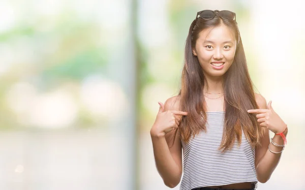 年轻的亚洲妇女戴着太阳镜在孤立的背景下 脸上露出自信的笑容 用手指自豪和快乐地指着自己 — 图库照片