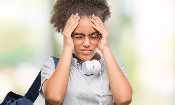 必死と強調した頭痛に苦しんで孤立の背景にヘッドフォンとバックパックを着ている若いアフロ アメリカ人学生女性の痛みと片頭痛 頭に手 — ストック写真