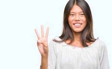 Genç Asyalı kadın gösterilen ve parmakları ile işaret izole arka plan üzerinde üçüncü ise kendinden emin ve mutlu gülümseyerek.