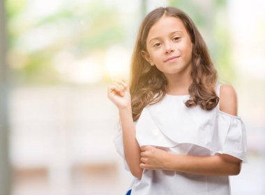 Esmer Latin kız kameraya bakarak yan el ve parmak ile işaret yüzünde kocaman bir gülümseme ile.