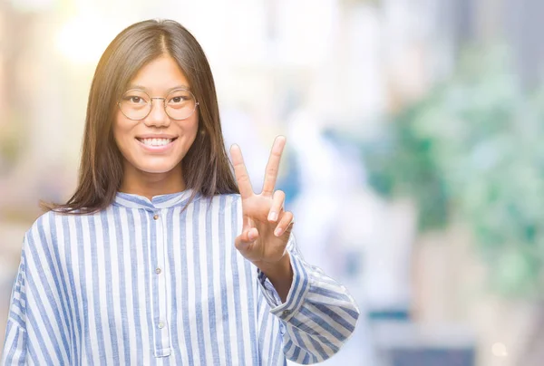 勝利のサインを行うカメラでウィンクしている幸せそうな顔を浮かべて孤立の背景の上の若いアジア女性 — ストック写真