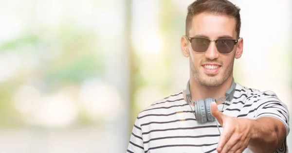 Όμορφος Νέος Άνθρωπος Φορώντας Ακουστικά Χαμογελώντας Προσφέροντας Φιλική Χειραψία Χαιρετισμό — Φωτογραφία Αρχείου