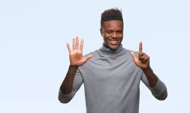 Gösterilen ve parmakları ile işaret izole arka plan üzerinde genç Afro-Amerikan adam kendinden emin ve mutlu gülümseyerek süre yedi numara.