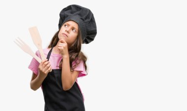 Esmer Latin kız Cook Tekdüzen ciddi yüz düşünme hakkında soru, çok karışık fikir giyiyor