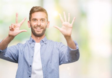 Gösterilen ve parmakları ile işaret izole arka plan üzerinde beyaz t-shirt giyen genç yakışıklı adam kendinden emin ve mutlu gülümseyerek süre sekiz numara.