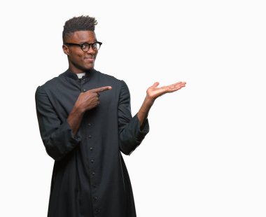 Genç Afro-Amerikan rahip adam üzerinden hayran ve el ile sunulması ve parmak ile işaret ederken kameraya gülümseyen izole arka plan.