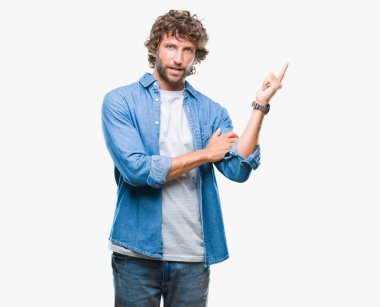 Kameraya bakarak yan el ve parmak ile işaret eden yakışıklı İspanyol modeli adam yüzünde kocaman bir gülümseme ile izole arka plan üzerinde.