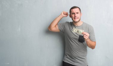 Gri grunge duvar gösteren bir dolar rahatsız Genç beyaz adam ve boşa çıkarmak ile öfke, çılgın ve yükseltilmiş eliyle diye bağıran öfke kavramı bağırarak.