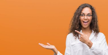 Hayret ve el ile sunulması ve parmak ile işaret ederken kameraya gülümseyen güzel genç İspanyol kadın.