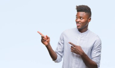 Gülümseyen ve iki elleri ve parmakları ile tarafına işaret kamera bakarak izole arka plan üzerinde genç Afro-Amerikan adam.