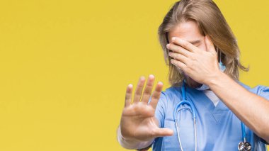 Sarı arka plan üzerinde uzun saçlı Genç yakışıklı erkek doktor