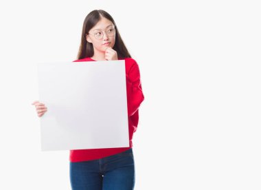 İzole arka plan boş afiş ciddi bir yüz düşünme hakkında soru, çok karışık fikir tutan genç Çinli kadın