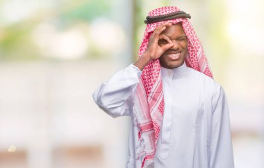 Geleneksel keffiyeh gülümsüyor, parmakları ile mutlu yüz üzerinden seyir göz el ile ok jest yapıyor izole arka plan üzerinde giyen genç Arapça Afrika adam.