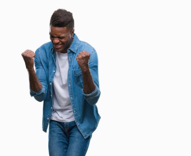 Gülümseyen ve başarı için çığlık genç Afro-Amerikan adam izole arka plan çok mutlu ve heyecanlı kaldırdı, silah ile kazanan jest yapıyor. Kutlama kavramı.