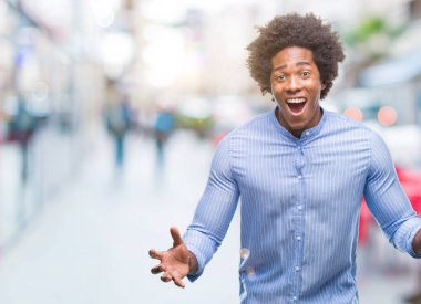 Afro Amerikalı adam deli kutluyor ve silah ile başarı için heyecanlı çığlık kaldırdı ve açık gözleri hayret izole arka plan üzerinde. Kazanan kavramı