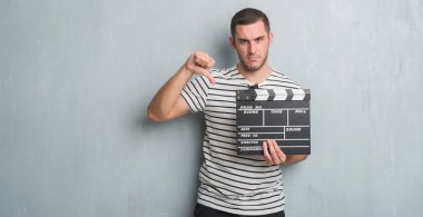 Beyaz delikanlı film fıçı tahtası kızgın yüzü, eksi işareti aşağı antipati başparmak ile gösterilen, ret kavramı ile tutarak gri grunge duvarın üzerinden