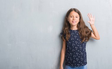 Genç İspanyol çocuğun gösterilen ve parmakları ile işaret grunge gri duvarın üzerinden beş kendinden emin ve mutlu gülümseyerek iken numara.