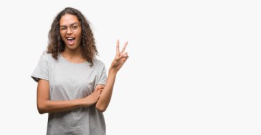 Mutlu yüz zafer işareti yaparken kameraya göz kırpıyor ile gülümseyen bardakları giyen güzel genç İspanyol kadın. İki numaralı.