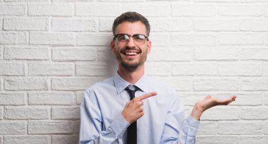 Beyaz tuğla duvar el ve parmak ile işaret çok mutlu üzerinde duran genç yetişkin iş adamı