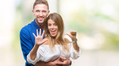 Gösterilen ve parmakları ile işaret izole arka plan üzerinde aşık genç çift altı kendinden emin ve mutlu gülümseyerek iken numara.