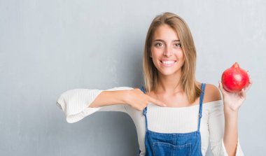 Grunge gri duvar nar sürpriz yüz işaret parmağı kendisine tutan güzel genç kadın