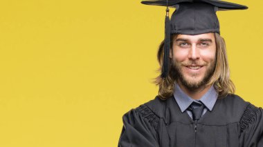 Genç yakışıklı adam uzun saçlı gülen surat ile gülümseyerek kameraya seyir silah geçti izole arka plan üzerinde mezun oldu. Olumlu bir kişi.