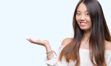 Neşeli sunulması ve kameraya bakarak avucunun ile işaret gülümseyen izole arka plan üzerinde Genç Asyalı kadın.