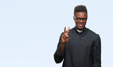 Genç Afro-Amerikan rahip adam gösterilen ve parmakları ile işaret izole arka plan üzerinde ikincisi ise kendinden emin ve mutlu gülümseyerek.