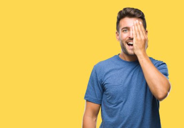 El yüz ve sürpriz duygu kendinden emin gülümseme ile tek gözüyle kapsayan izole arka plan üzerinde genç yakışıklı adam.