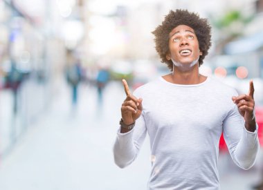 Afro Amerikalı adam izole arka plan üzerinden hayran ve yukarıya bakıp parmakları ile işaret şaşırttı ve silah kaldırdı.