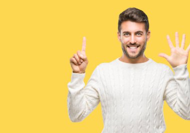 Gösterilen arka plan üzerinde kış kazak giyen genç yakışıklı adam izole ve parmakları ile işaret kendinden emin ve mutlu gülümseyerek süre 6 numara.