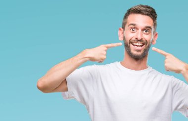 Tecrit edilmiş, güler yüzlü, kendine güvenen, parmaklarını, dişlerini ve ağzını gösteren genç yakışıklı bir adam. Sağlık kavramı.