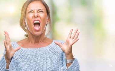 Üzerinde kış kazak giyen orta yaş üst düzey İspanyol kadın arka plan deli izole ve deli bağırarak ve agresif ifade ve silah kaldırdı bağırıyor. Hayal kırıklığı kavramı.