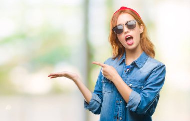 Genç güzel kadın üzerinden hayran ve el ile sunulması ve parmak ile işaret ederken kameraya gülümseyen güneş gözlüğü takıyor izole arka plan.