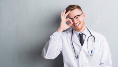 Gri grunge Duvar ile mutlu yüz el parmaklarının arasından seyir göz üzerinde ok işaretiyle yapıyor gülümseyen genç redhead Doktor adam