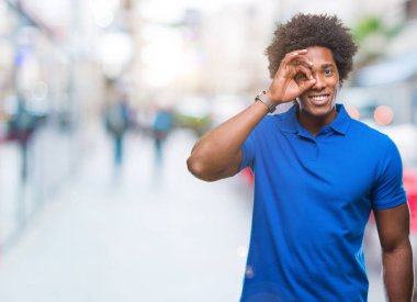 Afro Amerikalı adam gülümsüyor, parmakları ile mutlu yüz üzerinden seyir göz el ile ok jest yapıyor izole arka plan üzerinde.