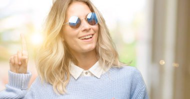 Uzak yan parmak ile işaret smartphone kullanan genç güzel kadın